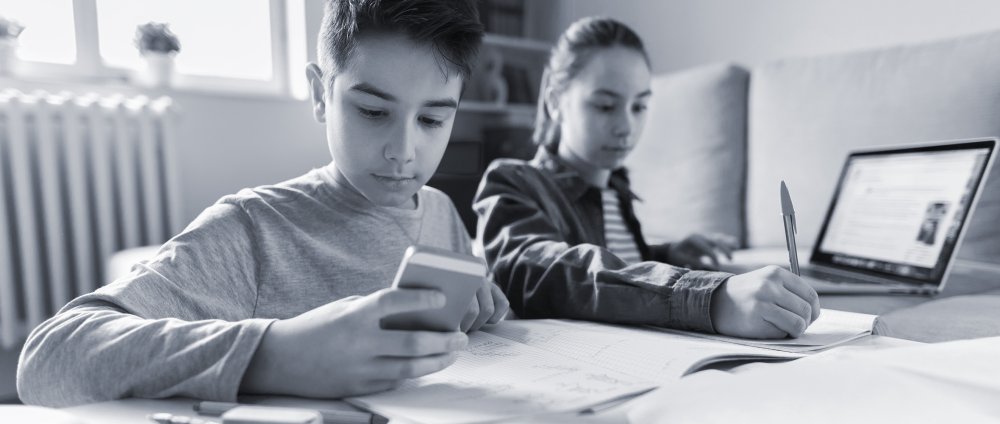 A brother and sister sitting in their livingroom completing writing assignments